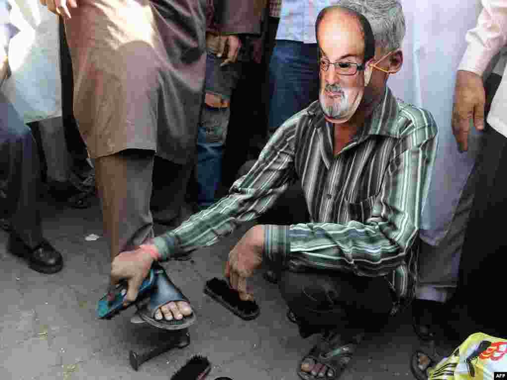 A cobbler wearing a Rushdie mask polishes shoes outside a mosque during a protest by an Islamic organization in Mumbai, India, in January 2012.