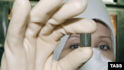 Работница Ульбинского металлургического комбината Елена Евсеева показывает произведенную тут таблетку уранового топлива. Иллюстративное фото. 