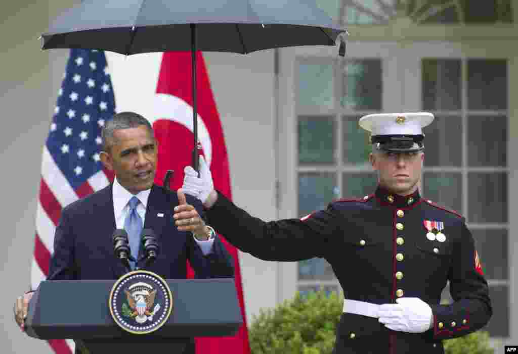 A U.S. Marine holds an umbrella for U.S. President Barack Obama as he held a joint press conference with Turkish Prime Minister Recep Tayyip Erdogan in the Rose Garden of the White House. (AFP/Saul Lo)