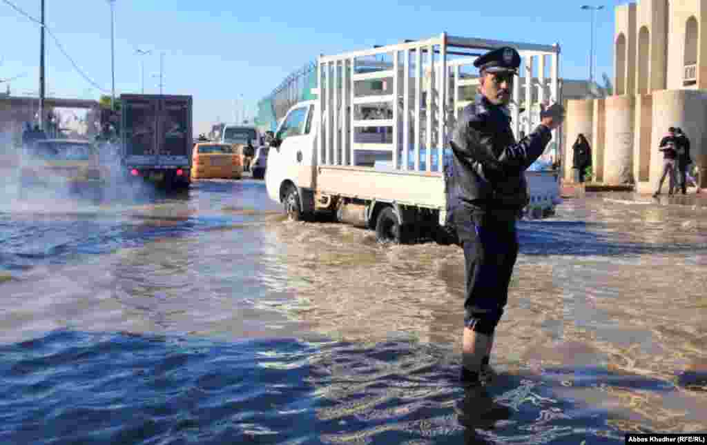 شرطي مرور يؤدي واجبه ورجله غاطسة في مياه الامطار 