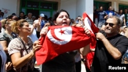 Assassinated Tunisian opposition politician Muhammad Brahmi's daughter Balkis (center) holds a Tunisian flag as she mourns his death in Tunis on July 25.