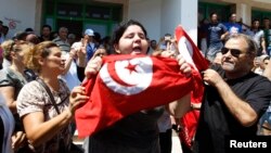 Assassinated Tunisian opposition politician Muhammad Brahmi's daughter Balkis (center) holds a Tunisian flag as she mourns his death in Tunis on July 25.