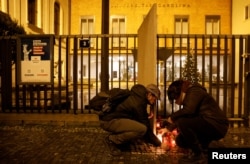 People light candles in front of the main building of Charles University following the mass shooting.