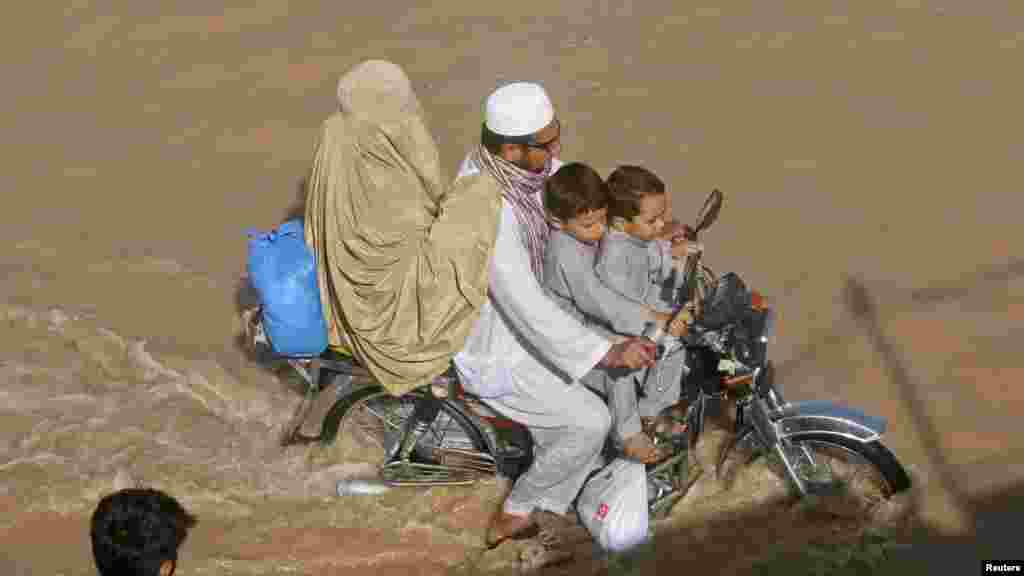 A family rides a motorbike through a flooded street after heavy monsoon rain in Peshawar, Pakistan. (REUTERS/Khuram Parvez)