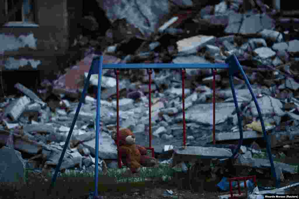 A teddy bear hangs on a swing next to a damaged building in the Saltivka district of Kharkiv, amid Russia&#39;s attack on Ukraine.