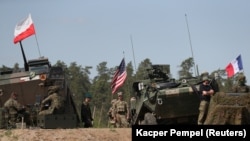 POLAND - U.S., Polish and French soldiers stand near their armoured vehicles during Defender Europe 2022 military exercise of NATO troops at the military range in Bemowo Piskie, May 24, 2022.