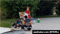 Turkmenistan. Woman with child in the park. Mask. Сhildren's car. Ashgabat. May, 2022