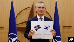 Генералниот секретар на НАТО Јенс Столтенберг ги прикажува документите со апликациите на Шведска и Финска за членство во Брисел, Белгија, среда, 18 мај 2022 година.