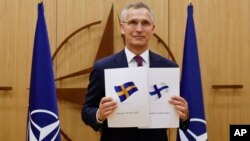 NATO Secretary-General Jens Stoltenberg displays documents as Sweden and Finland applied for membership in Brussels on May 18.
