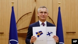 
Generalni sekretar NATO-a Jens Stoltenberg pokazuje dokumente da su Švedska i Finska podnele zahtev za članstvo, 18. maj 2022.
