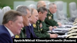Vlagyimir Putyin orosz elnök (balra a harmadik) a Nemzeti Védelmi Irányítóközpontban a nukleáris robbanófejek hordozására alkalmas Avangard hiperszonikus rakétarendszer tesztjén Moszkvában 2018-ban