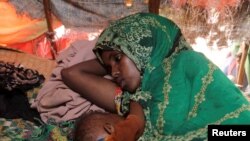 Një grua me foshnjën e saj tetëmuajshe, e zhvendosur në një kamp në Somali. Fotografi nga arkivi.