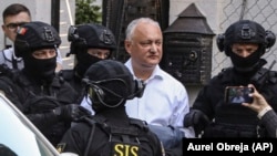 Ofițeri ai Serviciului de Informații și Securitate îl escortează pe fostul președinte Igor Dodon către o dubă, după ce acesta a fost reținut în casa sa din Chișinău, pe 24 mai 2022.