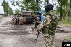 Представник так званої «народної міліції» незаконного збройного угруповання «ЛНР» біля розбитої військової техніки в Луганську