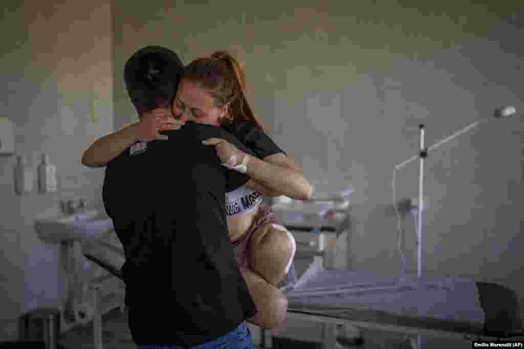 Oksana Balandina, 23, is carried by her husband, Viktor, at a hospital in Lviv on May 13, 2022. Oksana lost both legs and four fingers on her left arm when a shell exploded near her house. &quot;There was an explosion. My legs felt like they were falling into emptiness right after that. I was trying to look around and saw that there were no legs anymore -- only bones, flesh, and blood,&quot; she recalled.