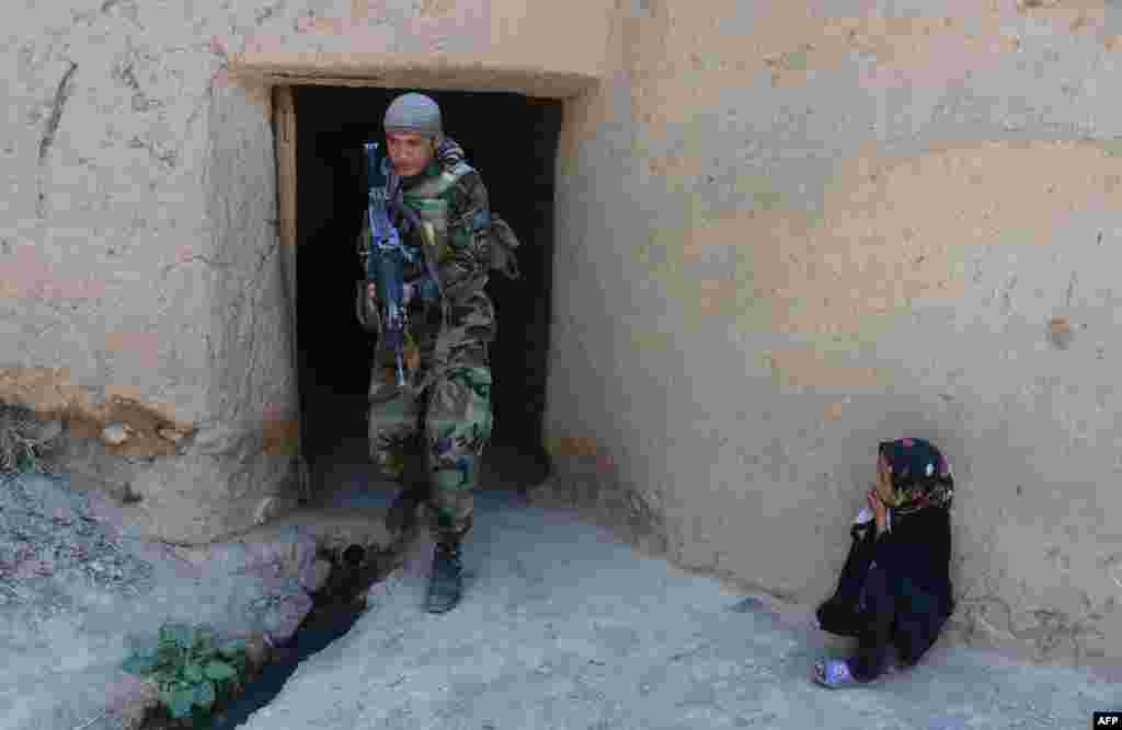 An Afghan girl watches an Afghan National Army (ANA) special-forces soldier as he patrols in the Gozara district of Herat. (AFP/Aref Karimi)