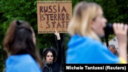 Un protestatar cu o pancartă în mână, pe care scrie „Rusia e un stat terorist”, în apropierea sediului cancelarului Germaniei, în timpul unui protest care condamnă atacurile Rusiei asupra civililor din Berlin, 8 iulie 2022.