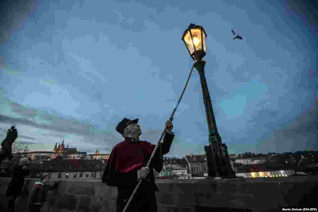 Ліхтаршчык Ян Татэр запальвае ліхтар на Карлавым мосьце ў Празе. 