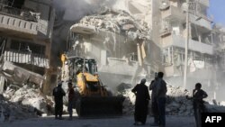 Civilians watch as a tractor clears the rubble following Syrian government air strikes in the rebel-held neighborhood of Tariq a-Bab in Aleppo on September 24.