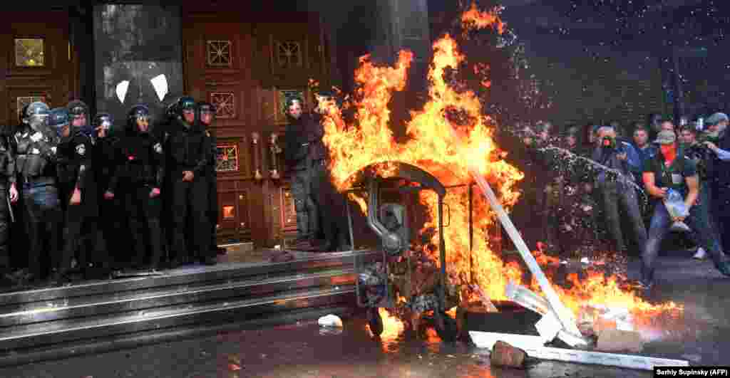 Ukrainian far-right activists set fire to a dumpster during clashes with riot police in front of the Prosecutor-General&#39;s Office in Kyiv on September 17. (AFP/Sergei Supinsky)