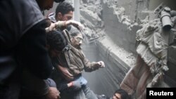 Rescue workers help a man from a shelter in the besieged town of Douma in eastern Ghouta Syria, on February 22. (Reuters/Eric Gaillard)