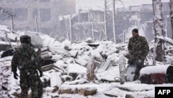 Syrian pro-government forces walk as snow falls in Aleppo on December 21.