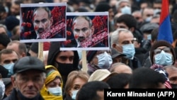 Луѓе држат постери на ерменскиот премиер Никол Пашинијан за време на митингот против контроверзниот мировен договор со Азербејџан во Ереван, 5 декември 2020 година