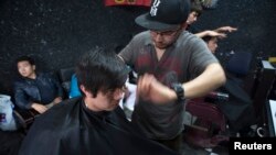 Një berber duke i prerë flokët një klienti në Kabul. Fotografi e vitit 2014.