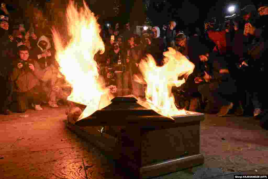 Demonstrators take photos of a coffin containing an image depicting Georgian billionaire Bidzina Ivanishvili during mass protests against the government&#39;s postponement of EU accession talks until 2028, in central Tbilisi.