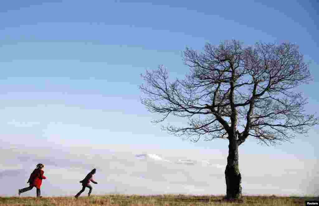 Children run as they play near a tree standing in front of fog over the central Bosnian town of Zenica in the Lisac mountain range.