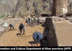 Afghan workers scramble to protect the minaret from floodwaters late last month.