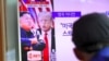 A man watches a television news program showing US President Donald Trump (C) and North Korean leader Kim Jong-Un (L) at a railway station in Seoul on August 9, 2017