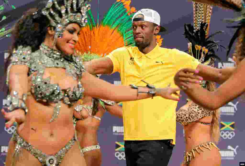 Sprinter Usain Bolt of Jamaica sambas with some dancers during a press conference.