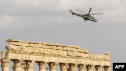A Russian attack helicopter flies above the damaged site of the ancient city of Palmyra in March