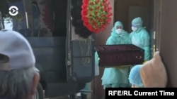 Медработники в защитных костюмах несут гроб возле морга в Алматы во время пандемии коронавируса.