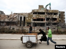 People push carts in front of the remnants of the Chinese Embassy during its demolition in Belgrade in 2010.