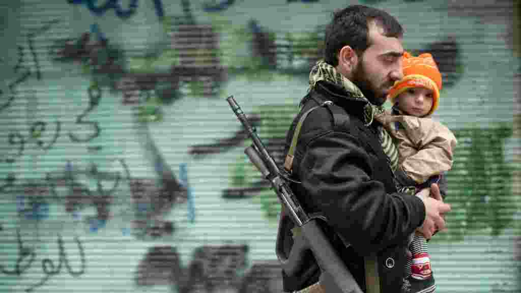 A rebel fighter carries his son in the embattled Syrian city of Aleppo. (AFP/Odd Andersen)