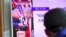 A man watches a television news program showing US President Donald Trump (C) and North Korean leader Kim Jong-Un (L) at a railway station in Seoul on August 9, 2017
