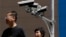 China US Trade - People walk by Chinese-made surveillance cameras installed along a street in Beijing, Thursday, May 23, 2019. The Chinese video surveillance company Hikvision says it is taking concern about the use of its technology seriously following a