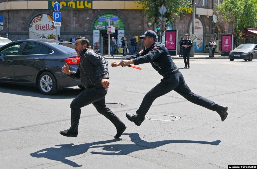 Një polic duke ndjekur një protestues që u arratis, Jerevan më 18 maj. Protestat kanë vazhduar në kryeqytetin armen që nga fillimi i muajit për shkak të frikës se kryeministri Nikol Pashinian mund të njohë zyrtarisht rajonin e diskutueshëm të Nagorno-Karabakut si territor të Azerbajxhanit.