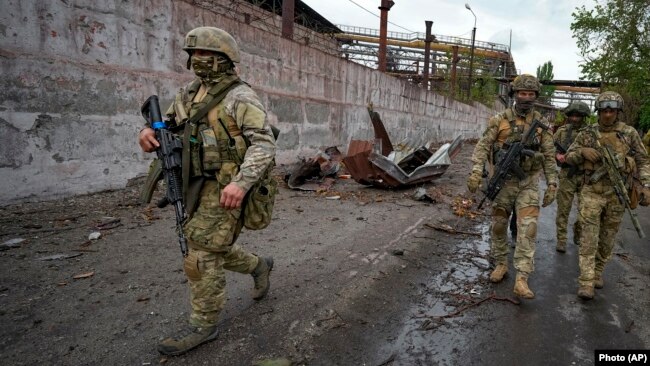 Russian soldiers patrol a destroyed part of Mariupol on May 18.