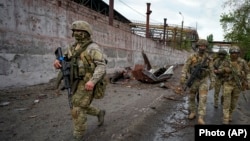 Руски војници патролираат во уништен дел од металуршкиот погон во Мариупол, на територијата под владата на проруските сепаратисти во источна Украина, на 18 мај