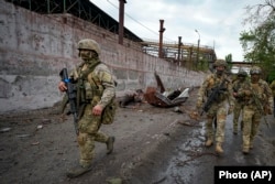 Russian soldiers patrol a destroyed part of the Illich Iron & Steel Works Metallurgical Plant in Mariupol, in territory under the government of pro-Russian separatist in eastern Ukraine, on May 18 during a trip organized by the Russian Ministry of Defense.