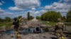 Ukrán katonák egy lebombázott hídnál Harkiv közelében 2022. május 16-án