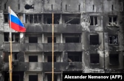 Российский флаг на фоне разрушенного дома в Мелитополе, апрель 2022 года