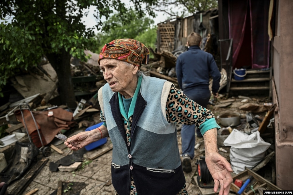 Një grua e moshuar shihet jashtë shtëpisë së saj të dëmtuar rëndë pasi ajo u godit nga një raketë në qytetin Bakhmut në Ukrainën lindore.