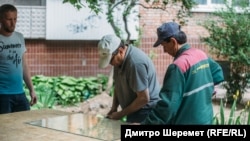 Коммунальщики в Запорожье, 25 мая 2022 года, когда российская ракета попала в ТРЦ в спальном районе