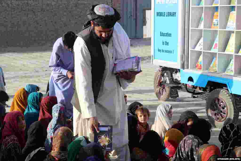 A volunteer distributes books to children.&nbsp;The mobile library includes books on history and geography as well as children&#39;s fiction in Pashto and Dari.