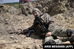 Un soldat ucrainean se adăpostește în timpul bombardamentelor rusești în afara orașului Lîsîchansk, pe 23 mai 2022.