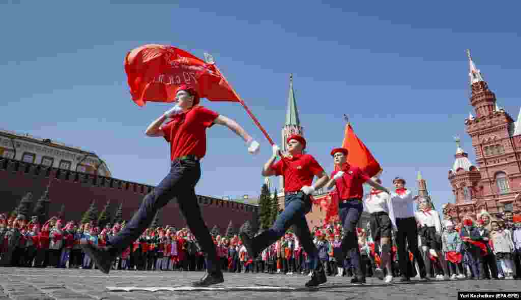 Российские дети маршируют под флагом с изображением коммунистического серпа и молота на Красной площади в Москве 22 мая 2022 года. Около 5000 школьников стали &laquo;всероссийскими пионерами&raquo; во время церемонии, организованной Коммунистической партией РФ 22 мая и изобилующей символикой социалистического прошлого России &nbsp;